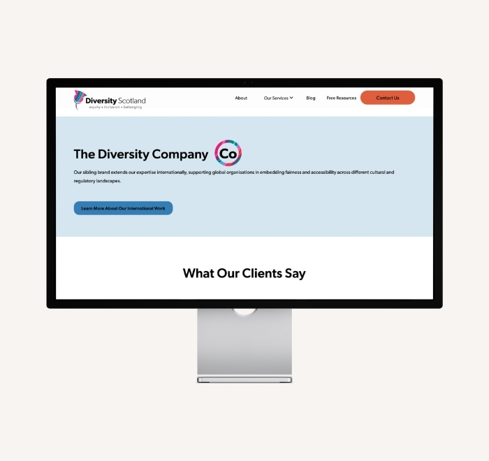 Large desktop monitor showing the page for The Diversity Company, with “what our clients say” section below the fold.