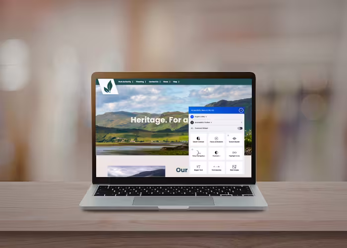 An open laptop on a desk showing a heritage website, with an accessibility plugin open