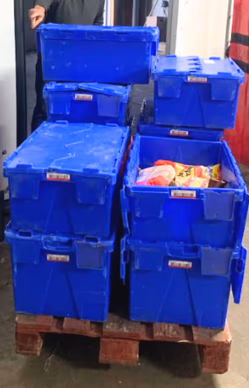 Des bacs bleus remplis de produits alimentaires destinés aux dons