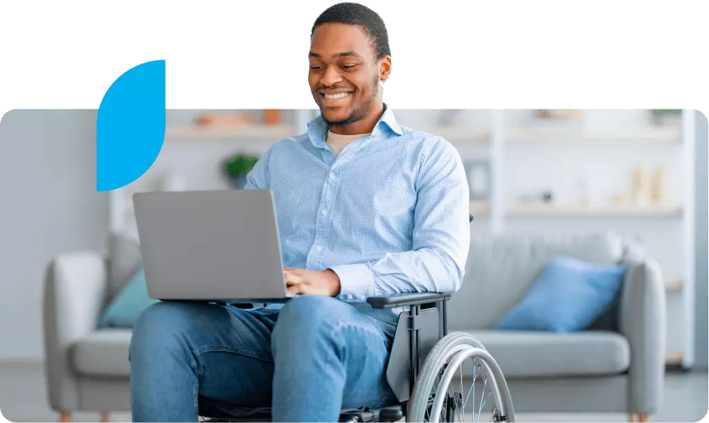 Treinamentos Gravados da Conta Azul. Homem em cadeira de rodas usando um laptop em um ambiente confortável e bem iluminado, mostrando acessibilidade e inclusão social.