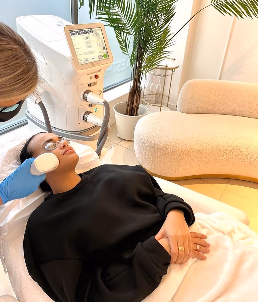 A person receiving a facial treatment from a technician in a clinic setting.