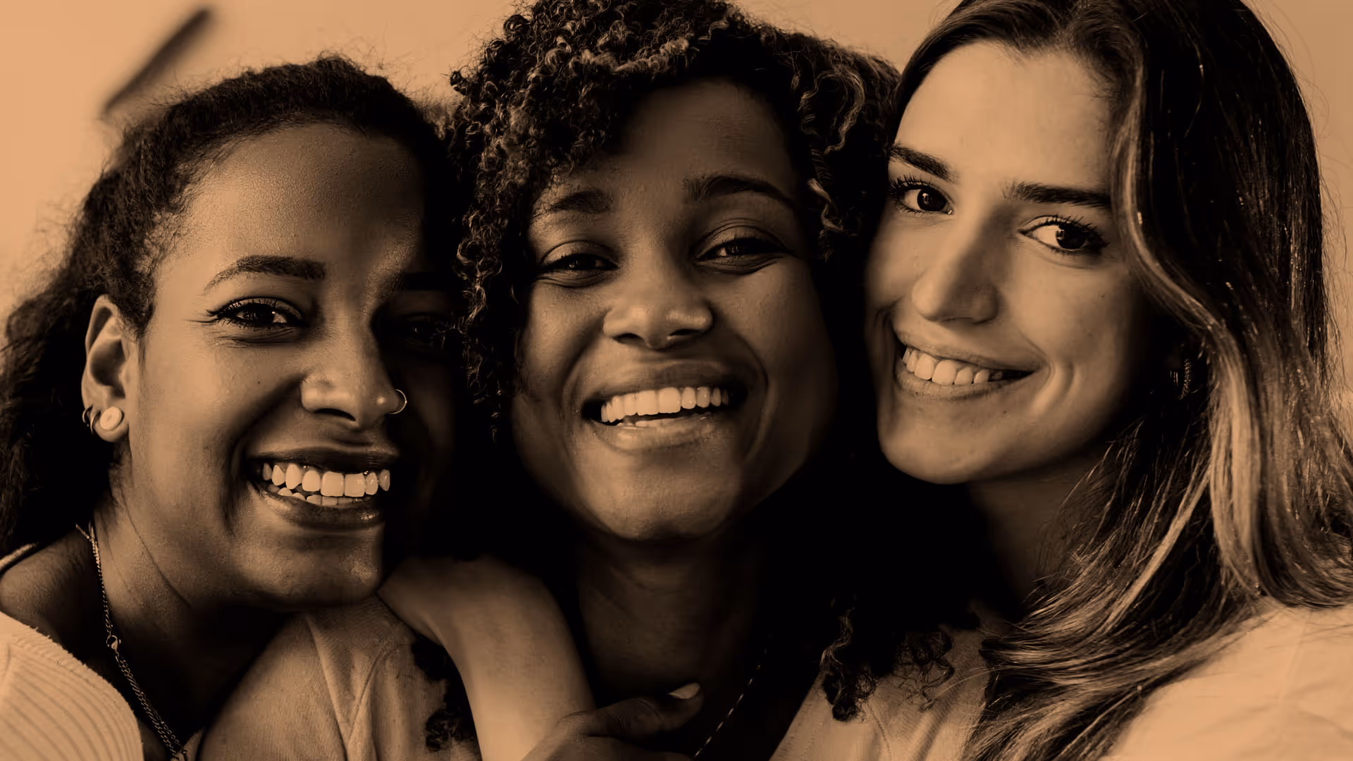 Three people smiling closely together, showing happiness and friendship.