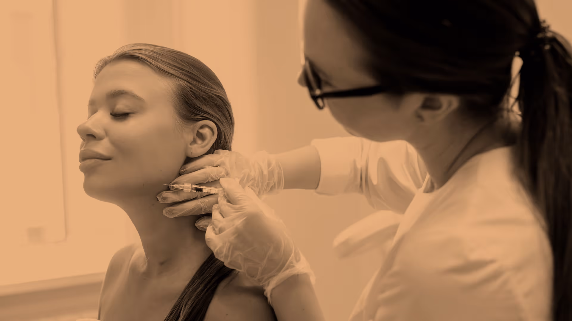 Person with gloves giving an injection to a woman's neck in a medical setting.