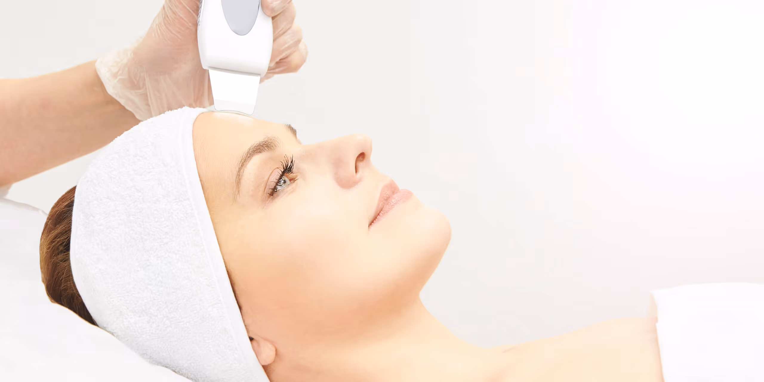 A person receives a facial treatment with a handheld device in a skincare clinic.