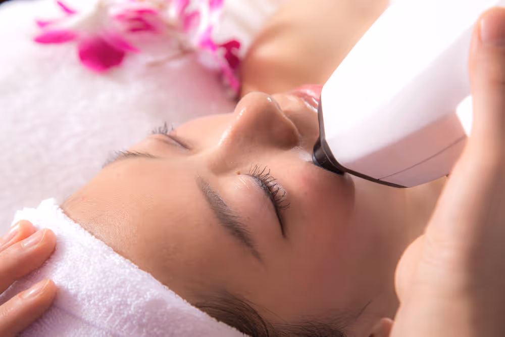 A person receives a facial beauty treatment with a handheld device at a spa.