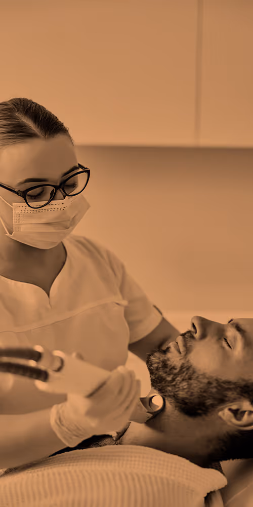 A healthcare professional performs a laser treatment on a man's face in a clinic.