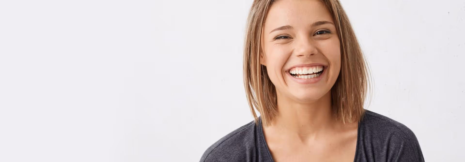 A woman with short brown hair is smiling warmly against a plain white background.