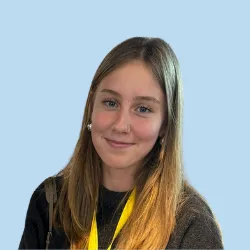 Lächelnde Person mit langen Haaren und gelbem Schal vor blauem Hintergrund