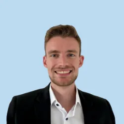 Lächelnder Mann im schwarzen Blazer vor hellblauem Hintergrund