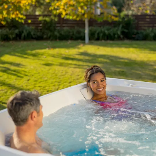 Zwei Personen entspannen im Whirlpool im Garten an einem sonnigen Tag