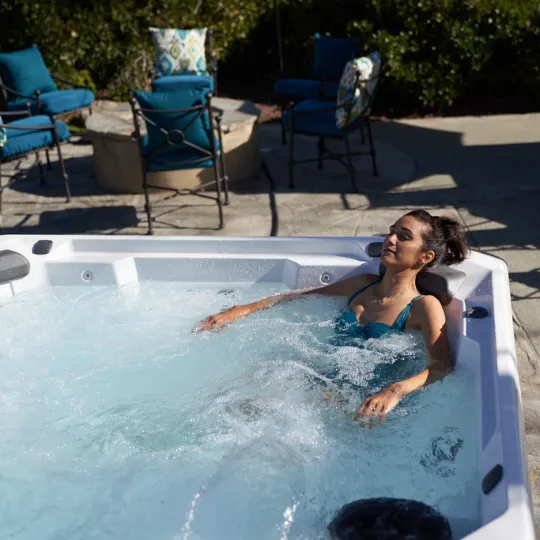 Frau entspannt sich in einem sprudelnden Whirlpool auf einer Terrasse im Freien