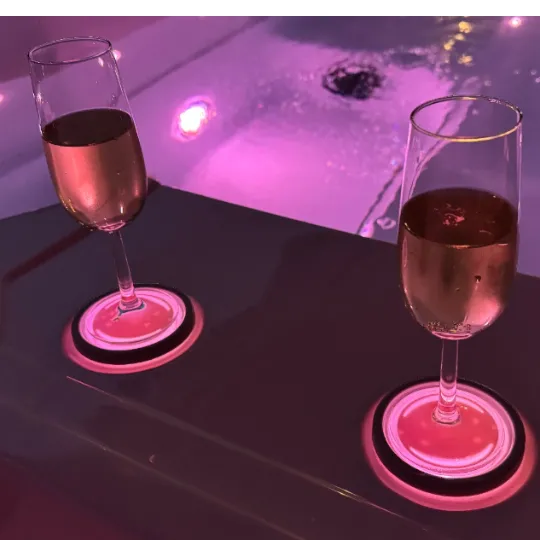 Zwei Weingläser mit rosa Beleuchtung auf einem dunklen Tisch