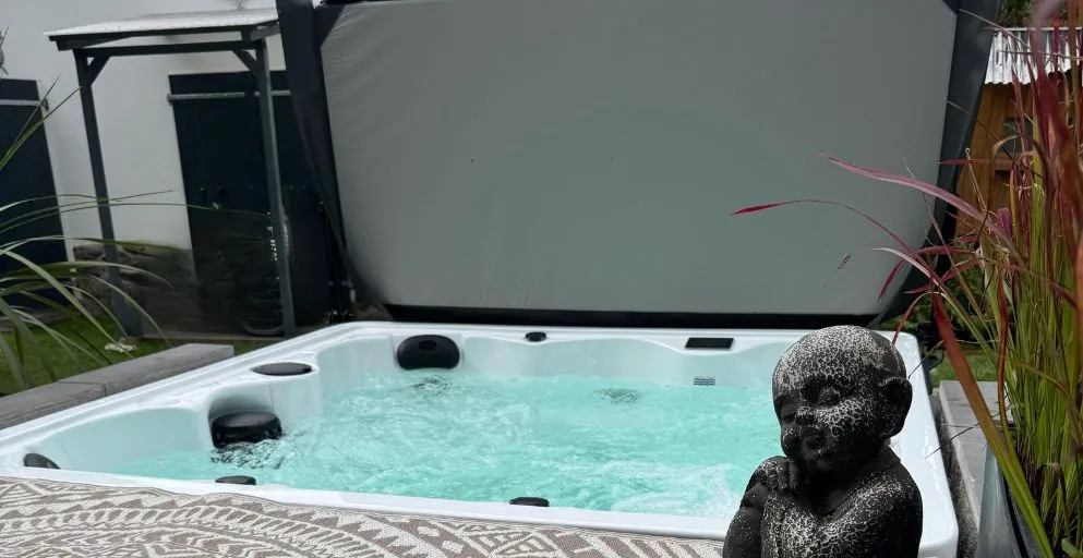 Whirlpool mit Steinstatue, umgeben von Pflanzen auf einer Terrasse