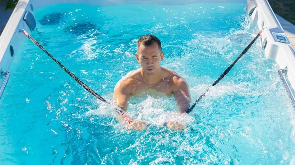 Schwimmer trainiert in blauem Wasser eines Pools mit Schwimmseilen