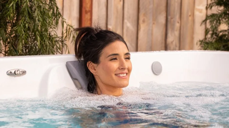 Lächelnde Person entspannt in einem sprudelnden Whirlpool im Freien