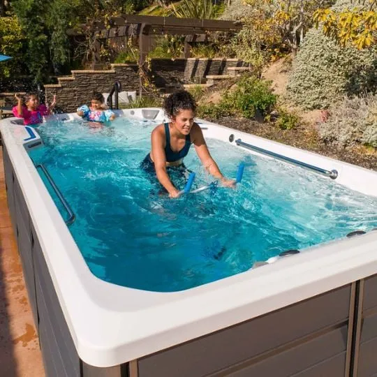 Familie entspannt im blauen Whirlpool im Garten mit Pflanzen