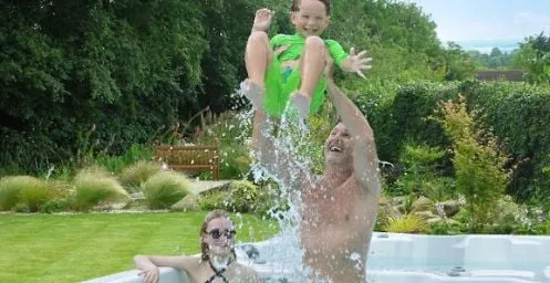 Kind springt in Pool, Wasser spritzt, Spaß im Garten an heißem Sommertag