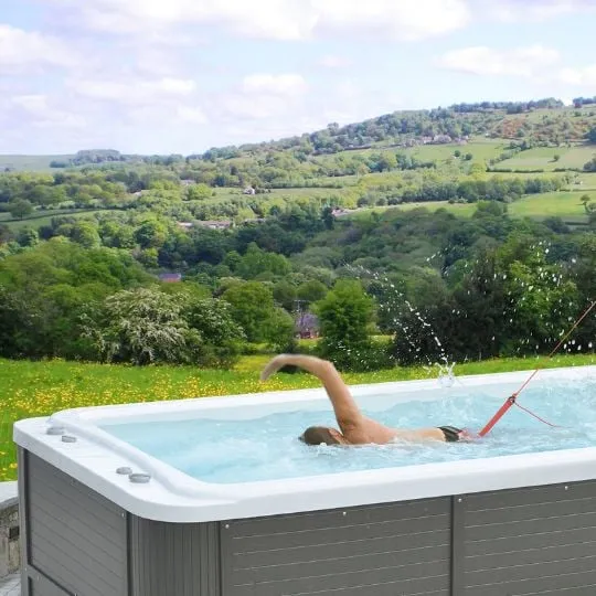 Whirlpool mit Schwimmer vor malerischer grüner Landschaft mit Hügeln
