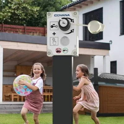 Zwei Mädchen spielen fröhlich mit einem Ball neben einer Covana-Steuerungstafel