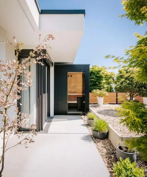 Moderner Eingang mit Blühbaum, Kieselsteinen und minimalistischer Architektur