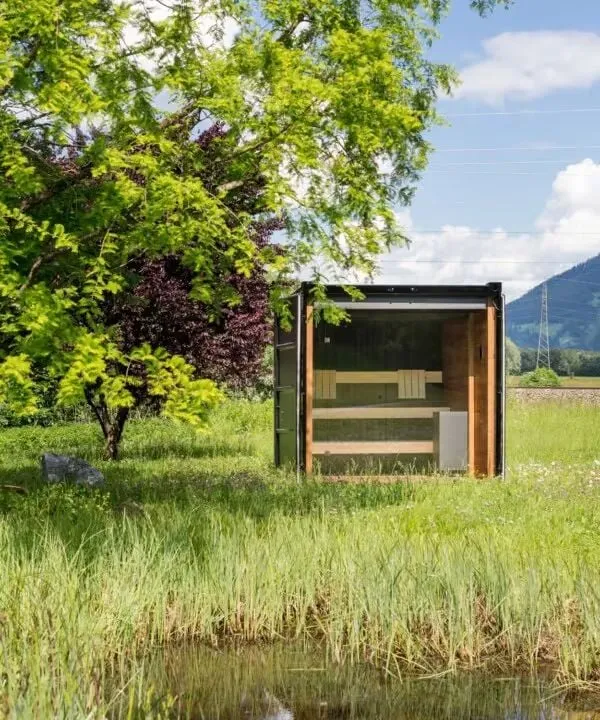 Modernes Gartenhaus neben einem grünen Baum in ländlicher Landschaft