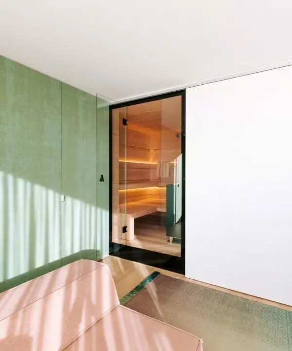 Moderner Saunaraum mit grüner Wand und Glasfront, warmes Holzinterieur