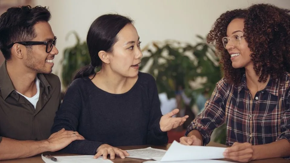 Drei Kollegen diskutieren freundlich über Dokumente im Büro