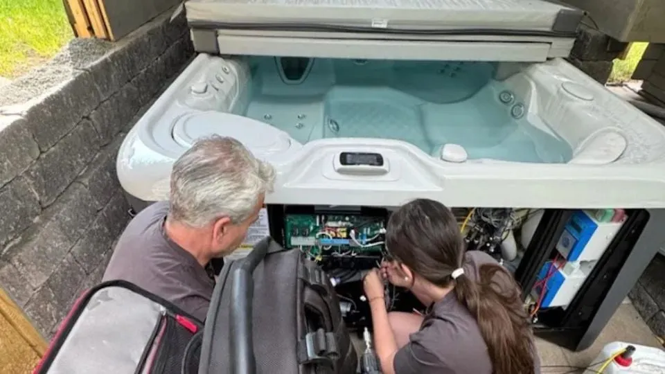 Zwei Personen reparieren zusammen einen Whirlpool mit offener Elektronik