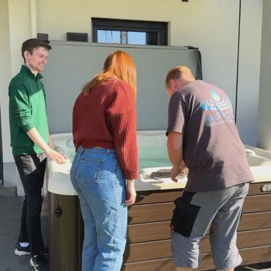 Drei Personen stehen um einen weißen Tisch in einem Büro oder Labor