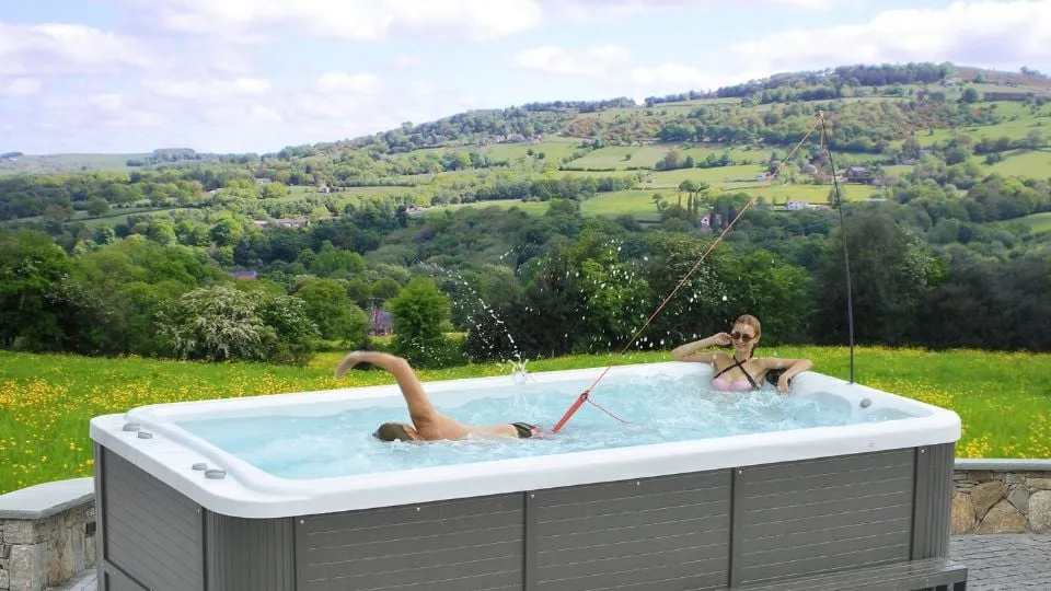 Whirlpool mit Personen vor malerischer grüner Landschaft mit Hügeln