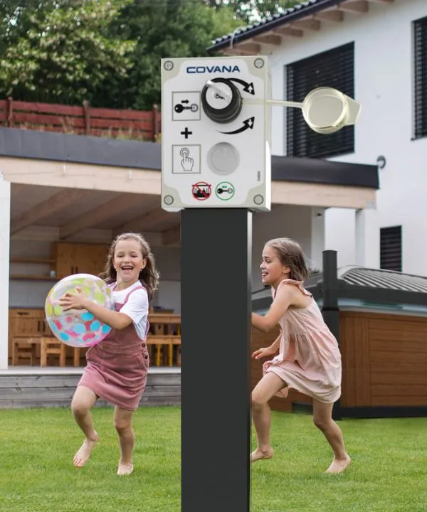 Zwei Mädchen spielen fröhlich mit einem Wasserball neben einer Covana-Steuereinheit
