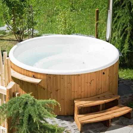 Runder herkömmliche Outdoor-Whirlpool mit Holzverkleidung und Treppe im sonnigen Garten.