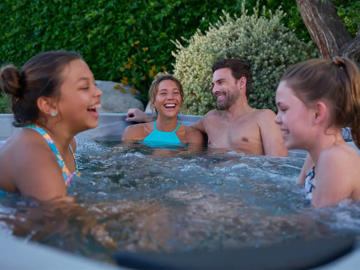 Familie genießt den erschwinglichen Hot Spring® FreeFlow® Whirlpool im Garten