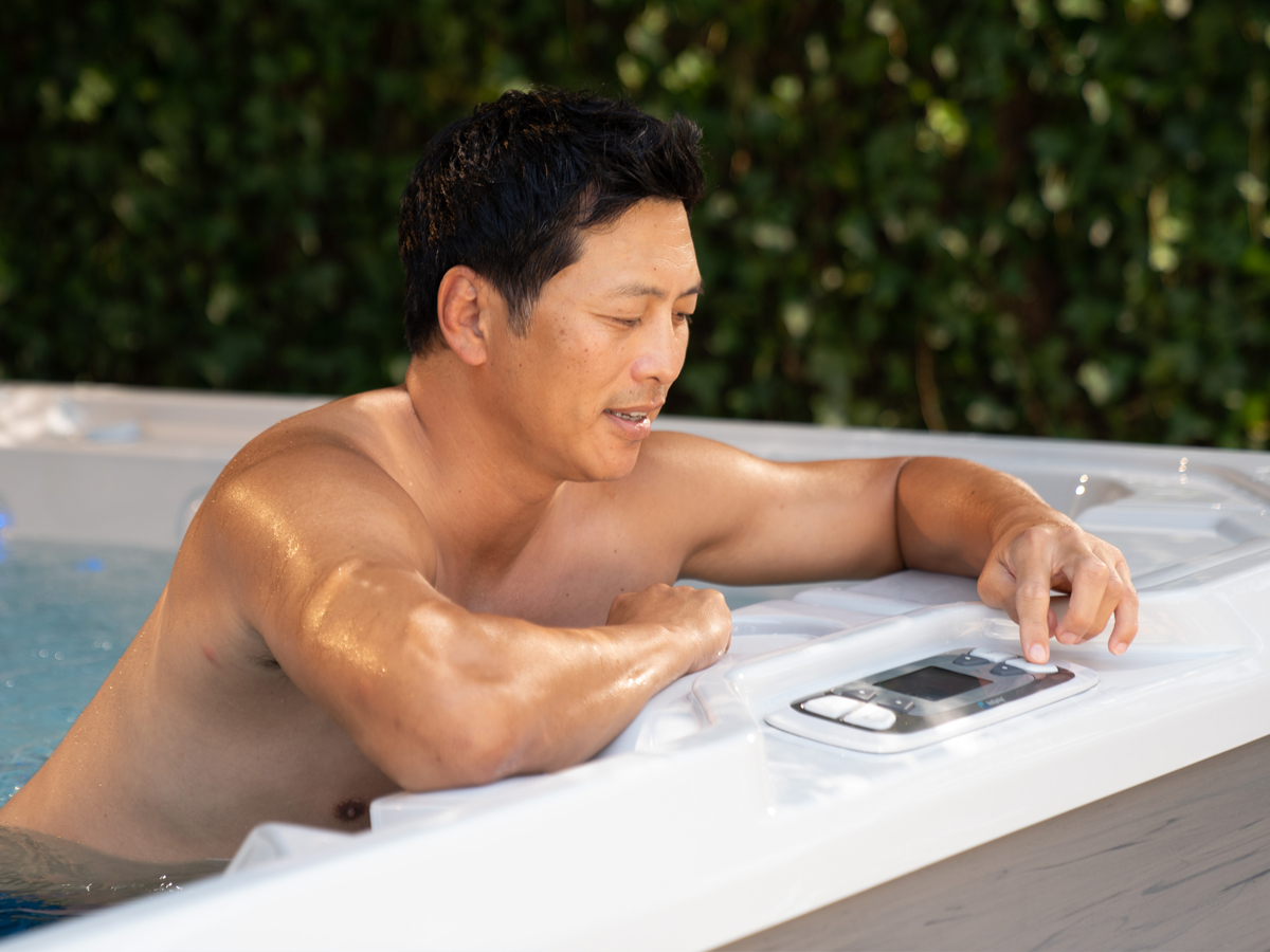 Mann bedient das Kontrollpanel am HotSpring Whirlpool – Wasserpflege-Dosierung auf Fingertipp
