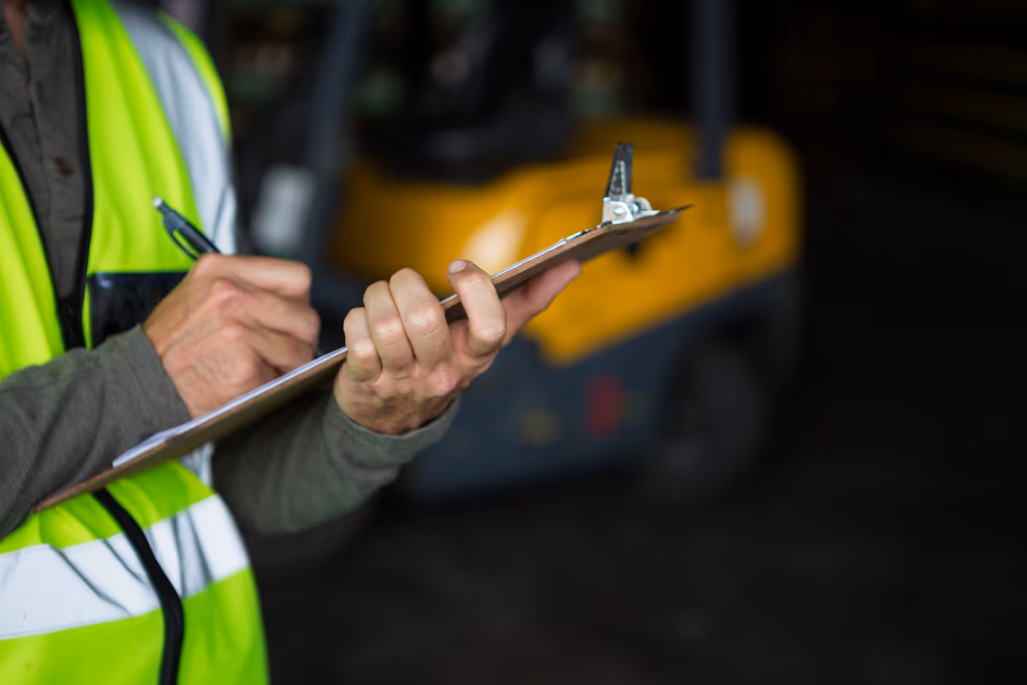 Un homme vêtu d'un gilet jaune tient un bloc-notes.