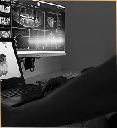 Schwarz-weiß-Aufnahme eines Zahnarztes, der digitale Röntgenbilder und 3D-Scans auf einem Monitor analysiert