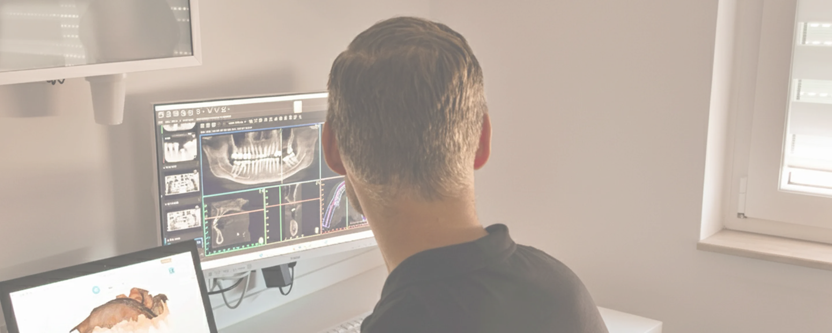 Zahnarzt betrachtet digitale Röntgenaufnahmen und 3D-Scans auf einem Monitor in einem modernen Behandlungsraum