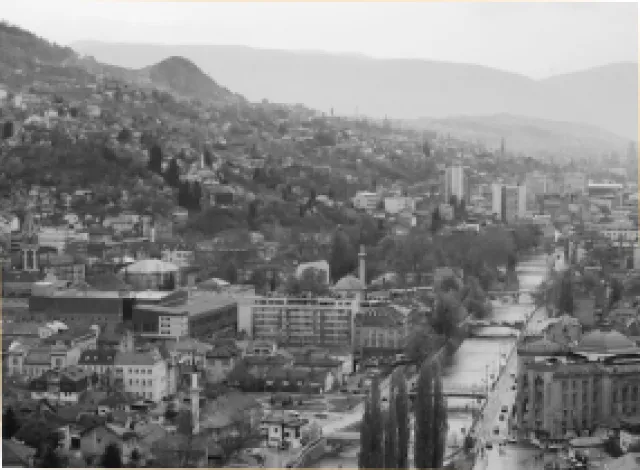 Schwarz-weiß-Panoramabild von Sarajevo mit dicht bebauten Hängen, historischem Stadtzentrum und Flusslauf
