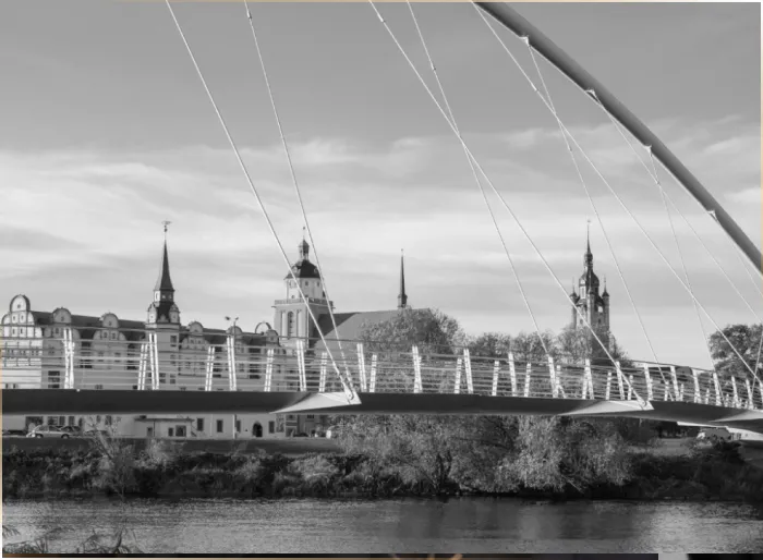 Schwarz-weiß-Aufnahme der Stadtsilhouette von Dessau mit moderner Bogenbrücke über der Mulde
