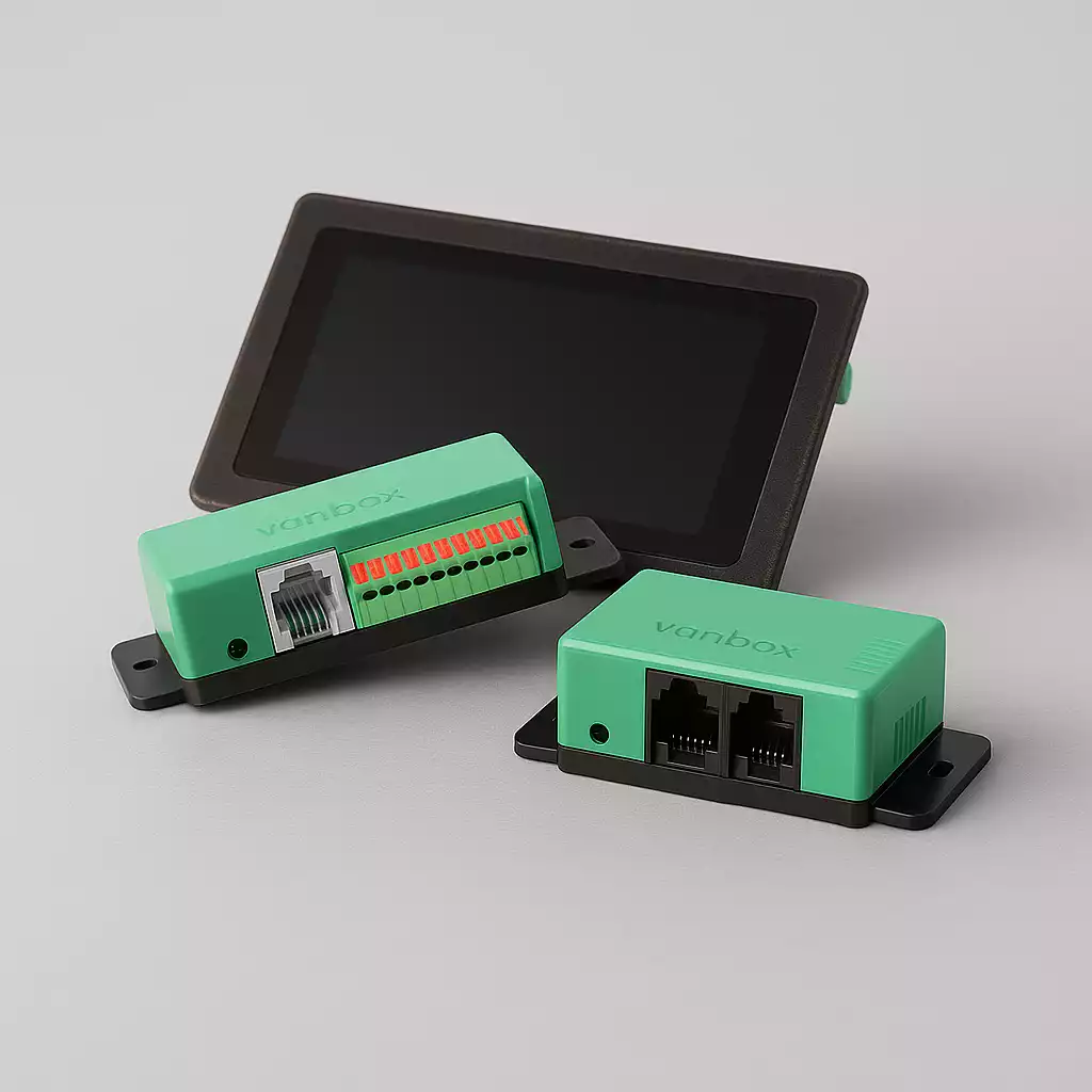 Two green Vanbox electronic modules with connectors placed in front of a black touchscreen device on a gray surface.