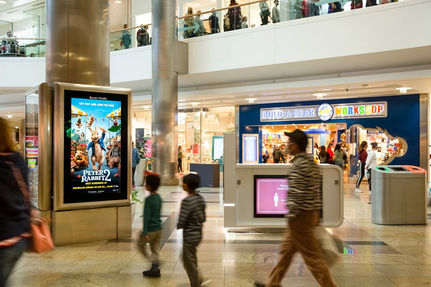 Digital screen in a busy shopping mall showing Peter Rabbit 2 ad