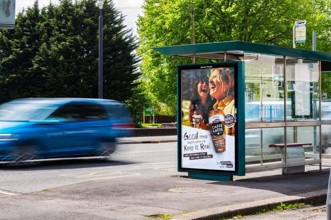 Emmi's caffe latte Adshel advertisement with two friends enjoying their barista quality coffee