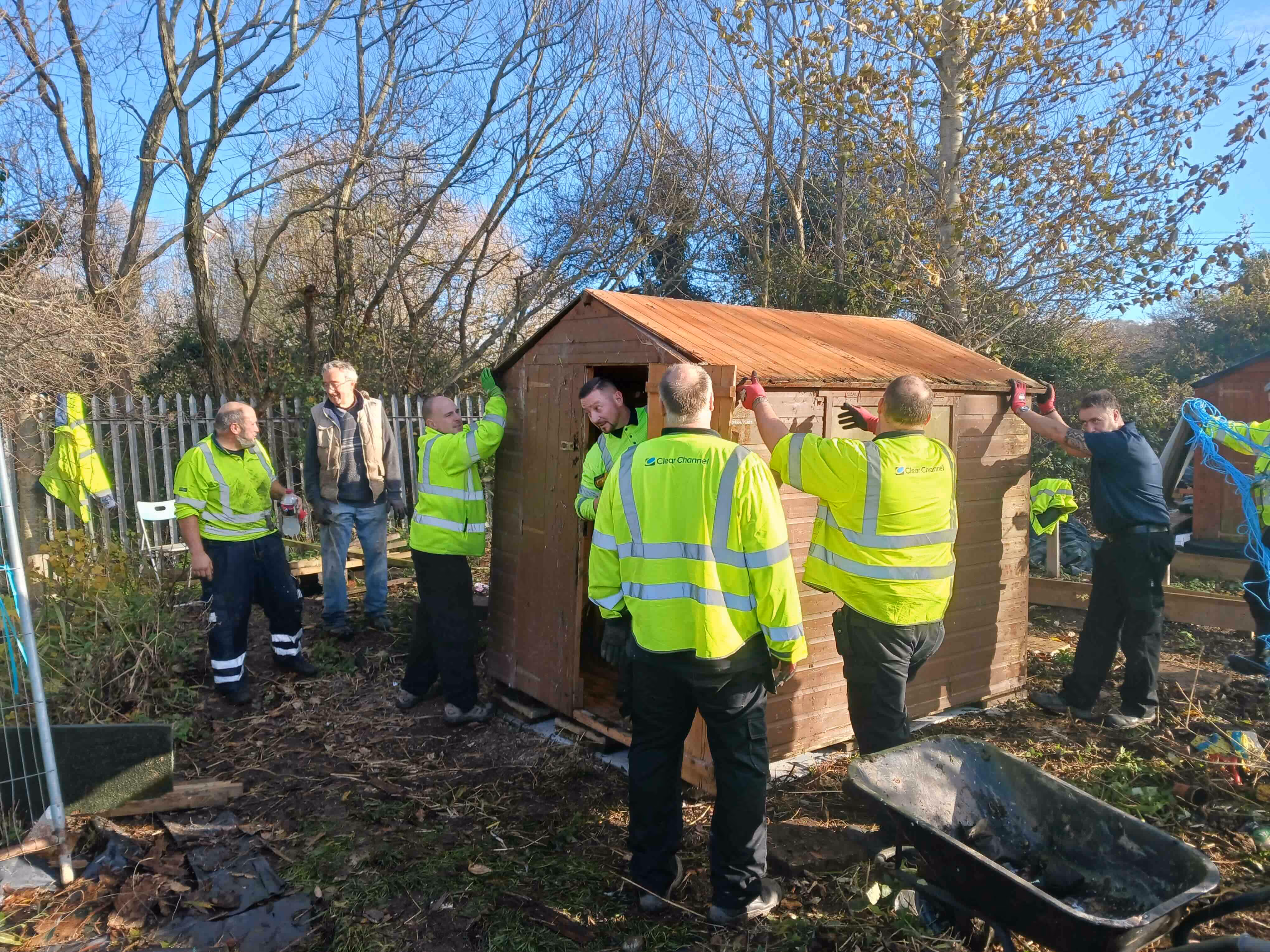 A group of men in reflective vests standing outside and working on a shed.