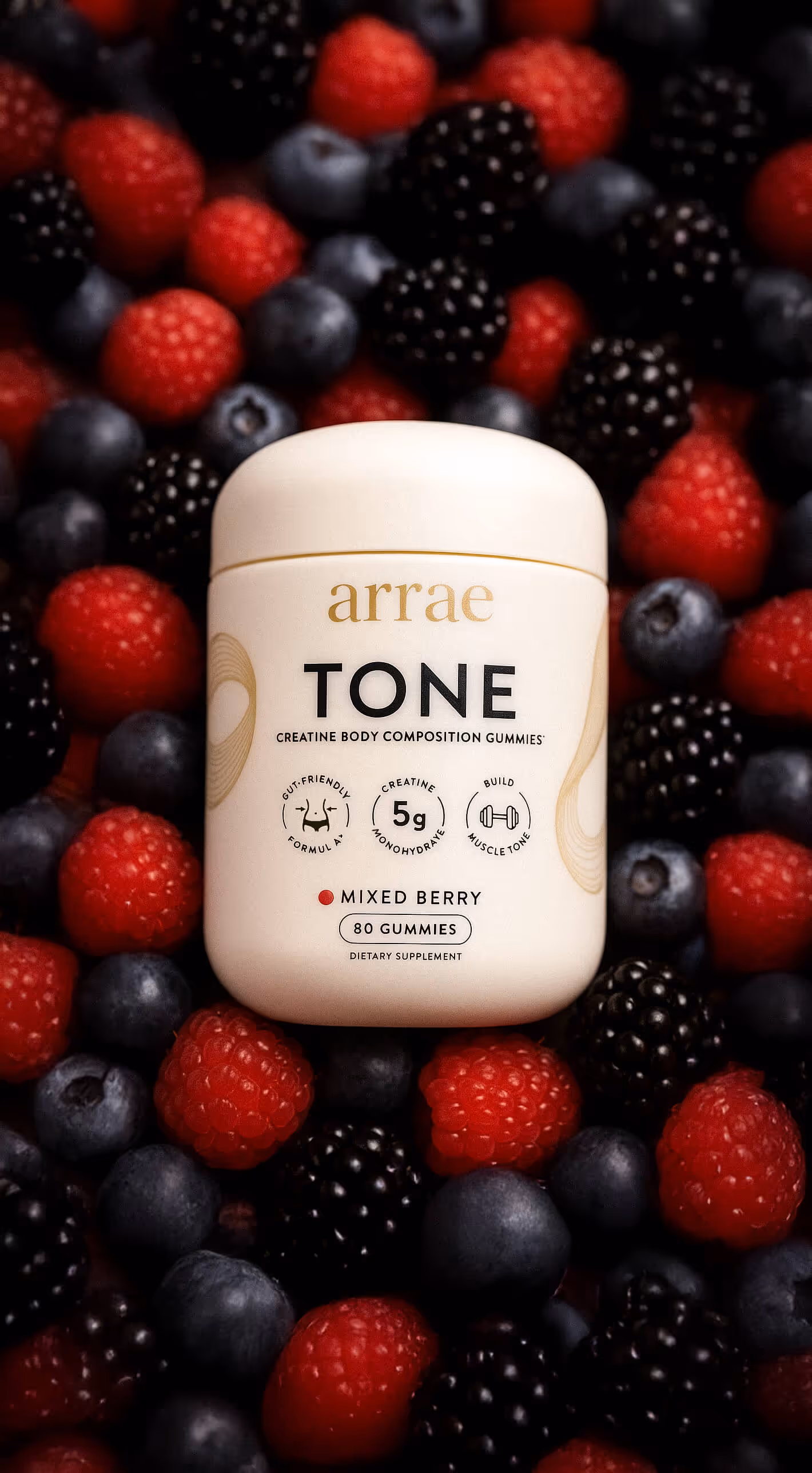 Jar of Arrae Tone creatine body composition gummies on mixed berries including raspberries, blackberries, and blueberries.