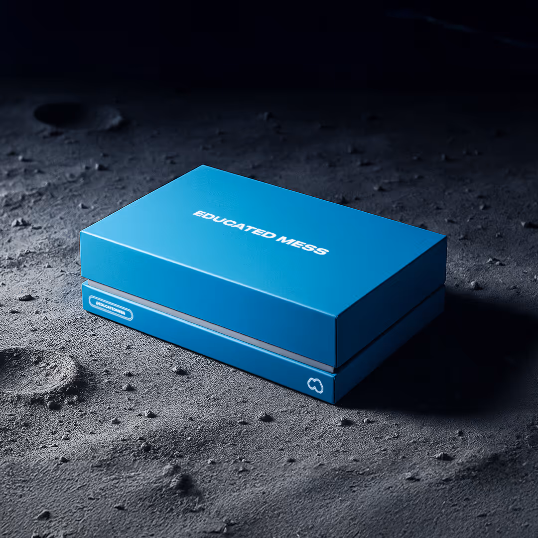 Blue rectangular box labeled 'EDUCATED MESS' resting on a textured dark surface resembling moon dust.