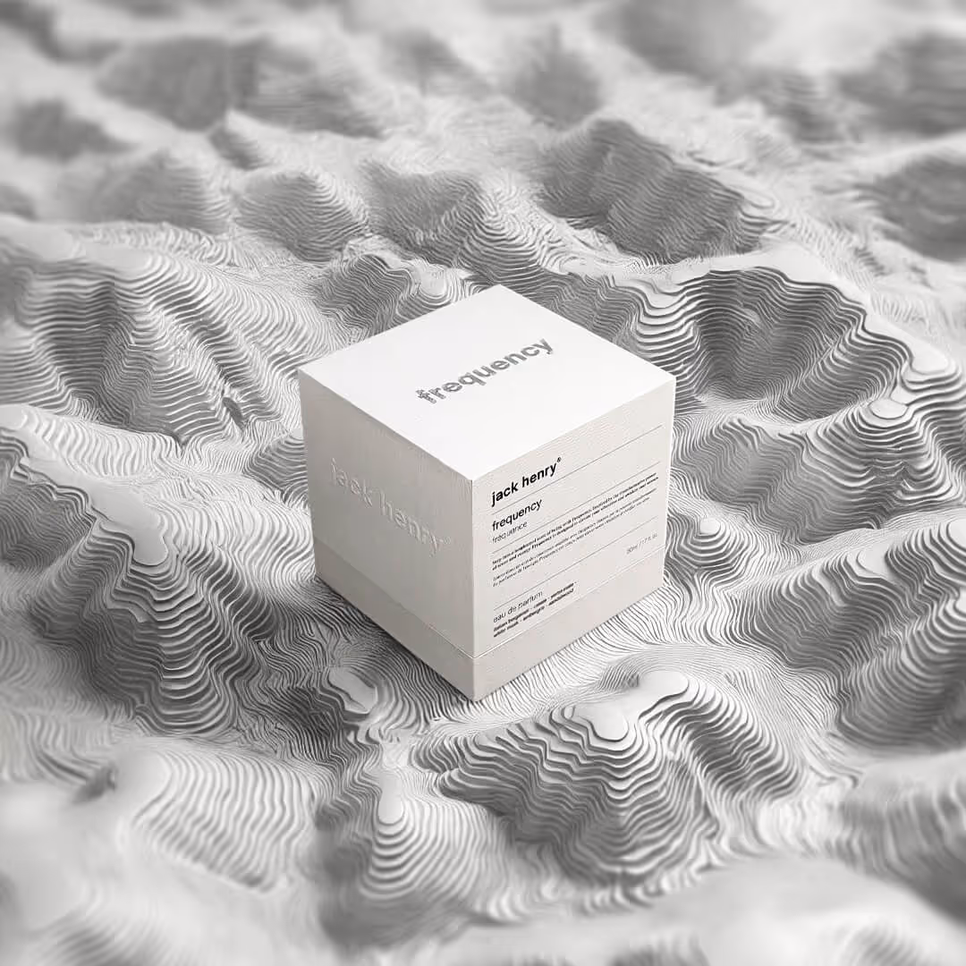 White cube-shaped packaging box labeled 'jack henry frequency' placed on a textured surface resembling topographic contour lines.