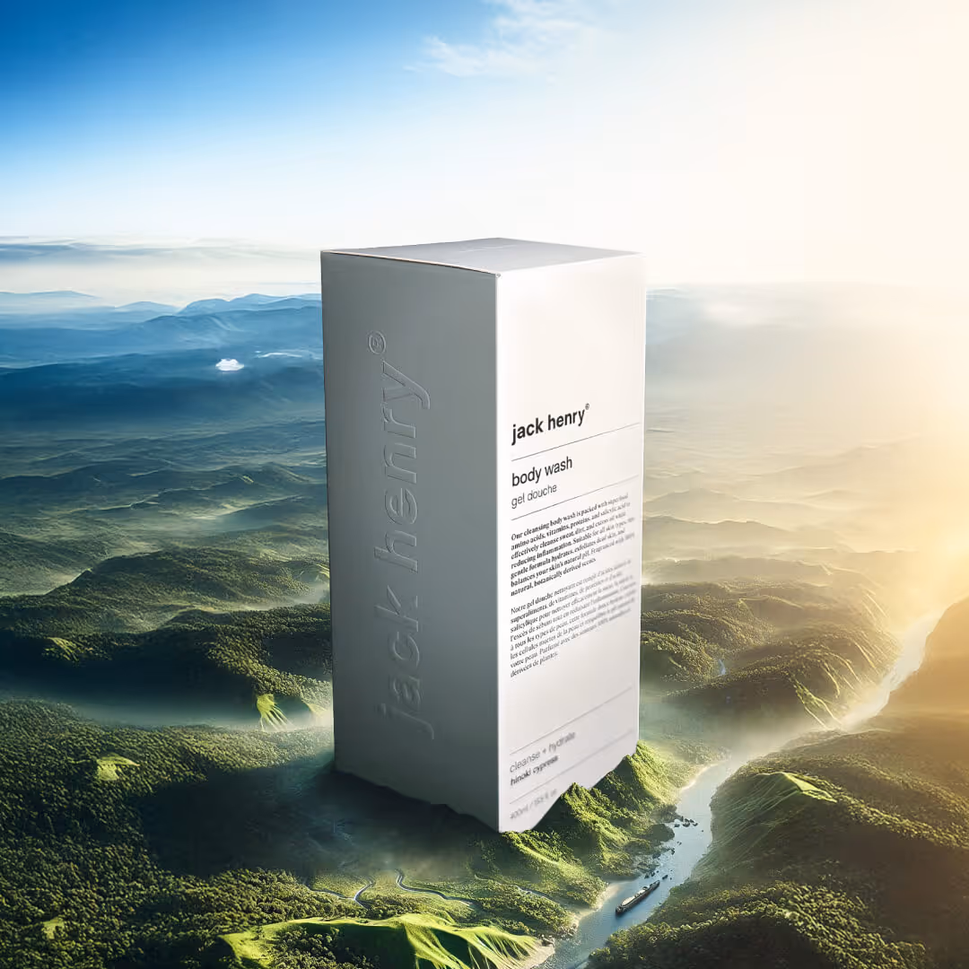 Jack Henry body wash box standing upright over a misty green mountainous landscape with a river and boat below.
