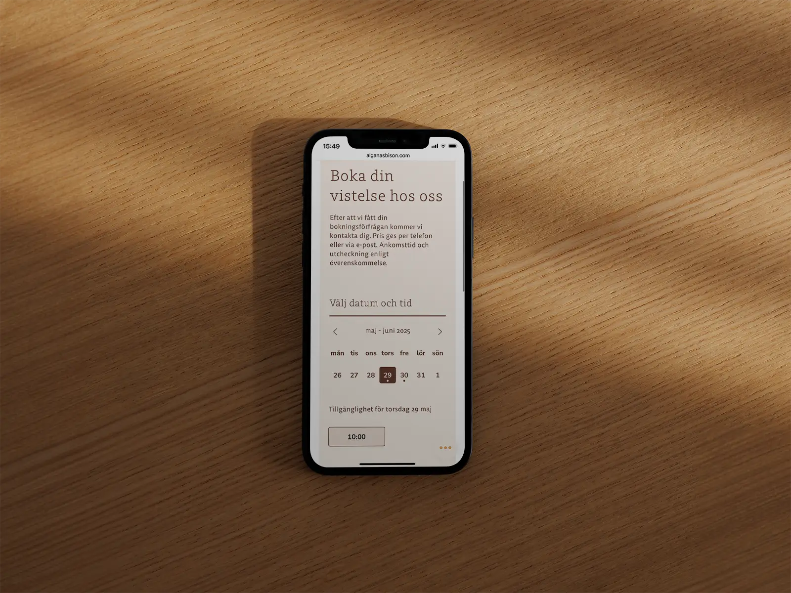 Smartphone on wooden surface displaying a booking page for selecting date and time in Swedish.