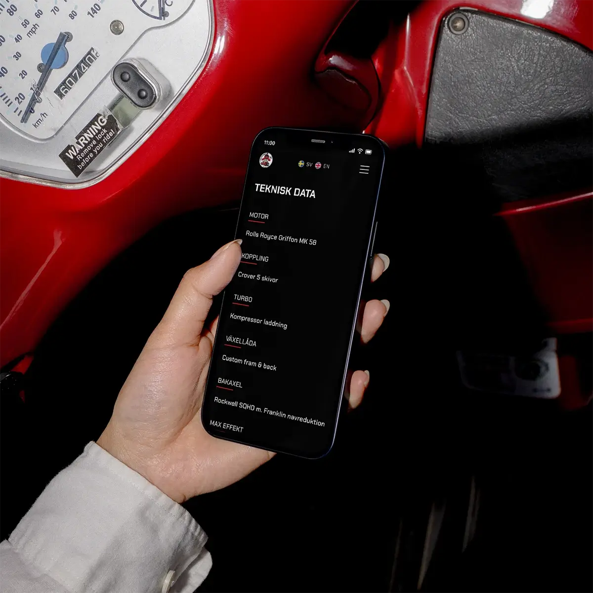 A person holding a smartphone displaying technical Tractor data in Swedish, with a red tractor and its speedometer visible in the background.