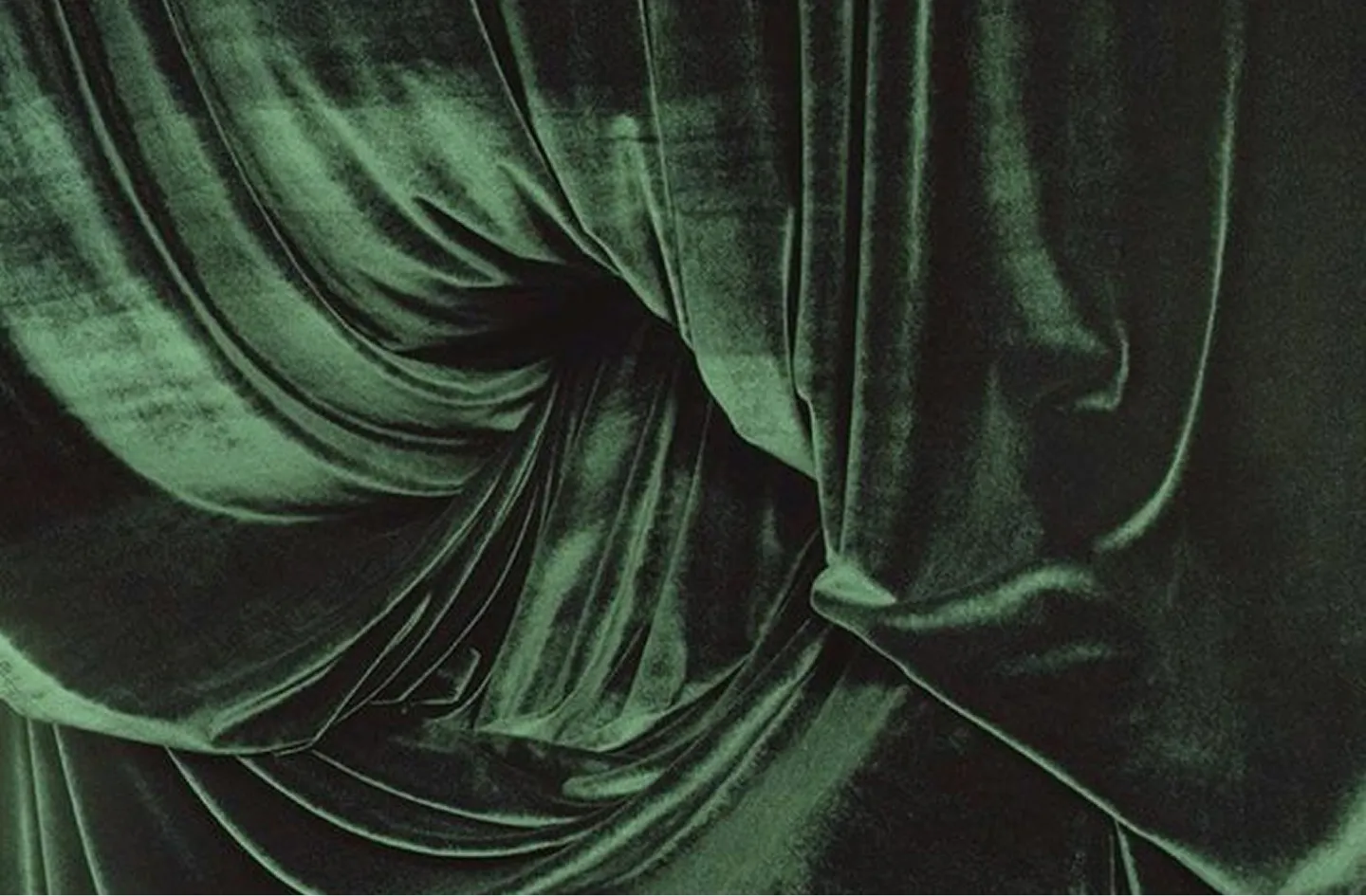 Close-up of dark green velvet fabric with soft folds and a twisted knot.